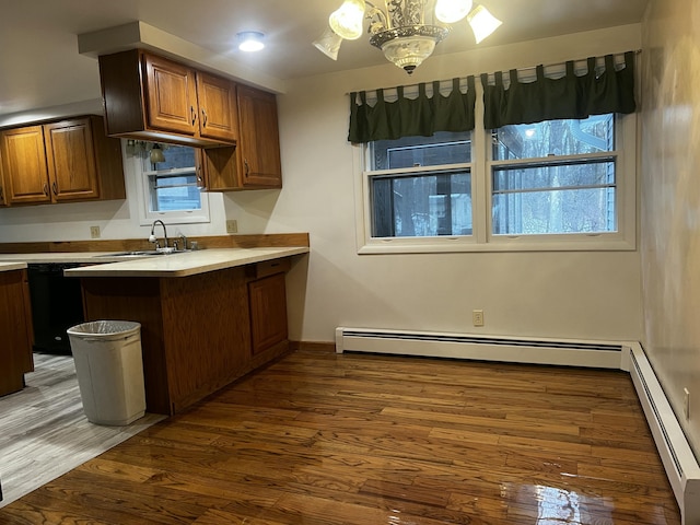 kitchen featuring kitchen peninsula, dark hardwood / wood-style flooring, baseboard heating, sink, and a notable chandelier