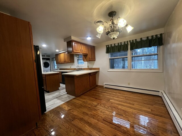 kitchen featuring hardwood / wood-style flooring, kitchen peninsula, baseboard heating, and a chandelier