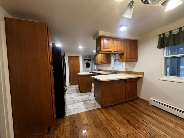 kitchen with sink, a baseboard radiator, black fridge, kitchen peninsula, and light hardwood / wood-style floors