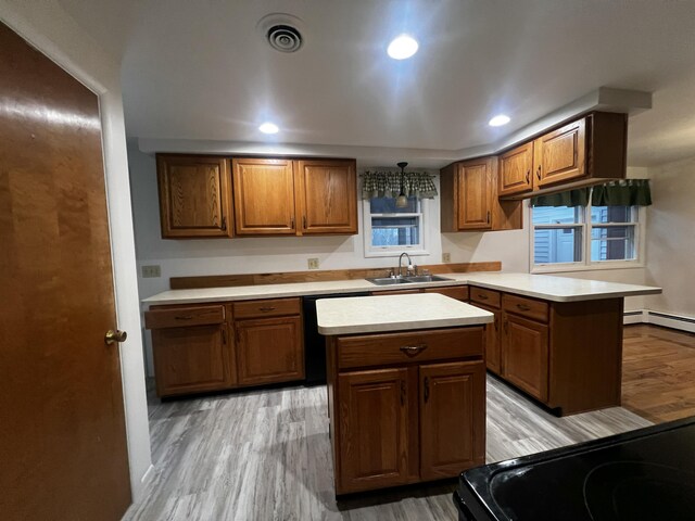 kitchen with a kitchen island, range, sink, and light hardwood / wood-style flooring