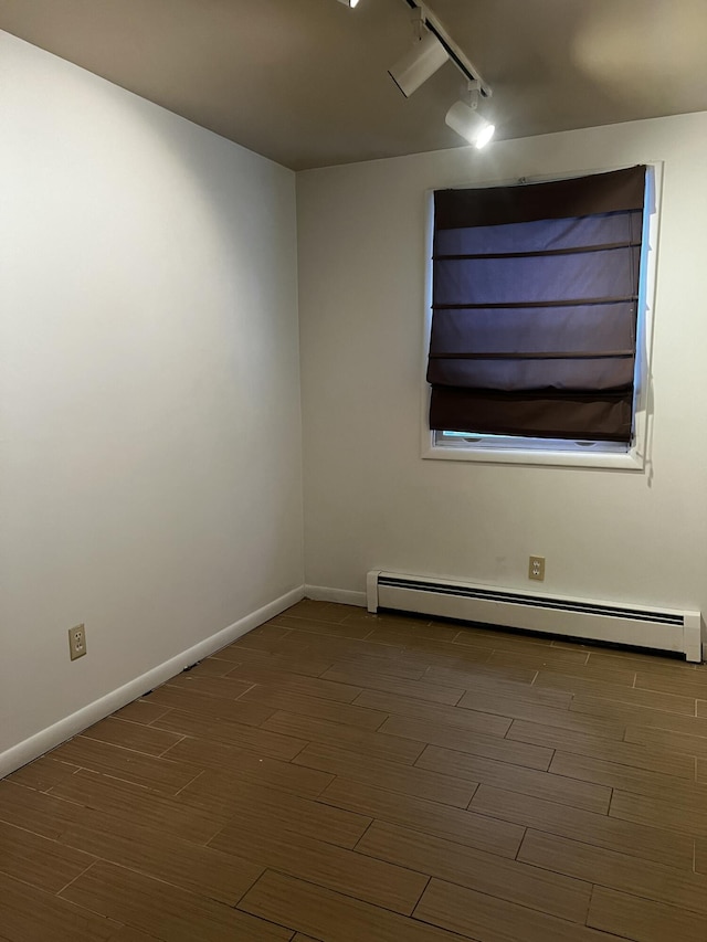 unfurnished room with rail lighting, dark hardwood / wood-style floors, and baseboard heating