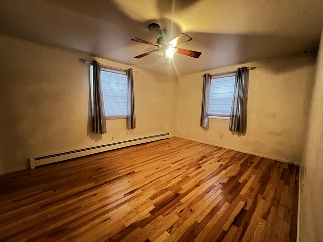 spare room with ceiling fan, a baseboard radiator, and wood-type flooring