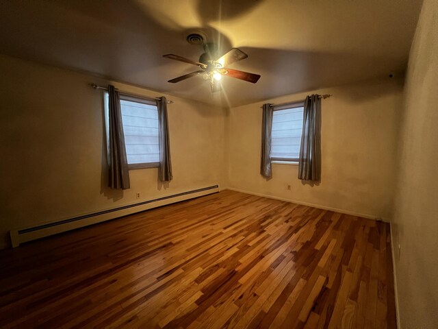 unfurnished room featuring hardwood / wood-style floors, ceiling fan, plenty of natural light, and baseboard heating