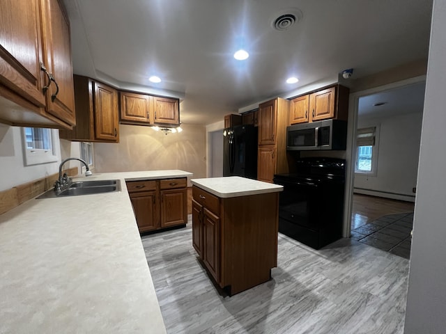 kitchen with black appliances, sink, light hardwood / wood-style floors, baseboard heating, and a kitchen island