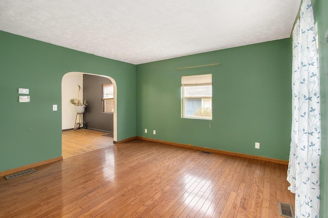 spare room with a textured ceiling and light wood-type flooring