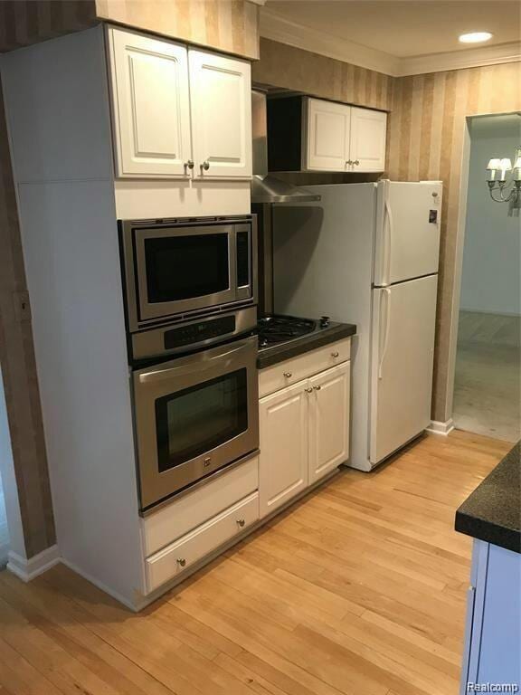 kitchen with white cabinets, appliances with stainless steel finishes, and an inviting chandelier