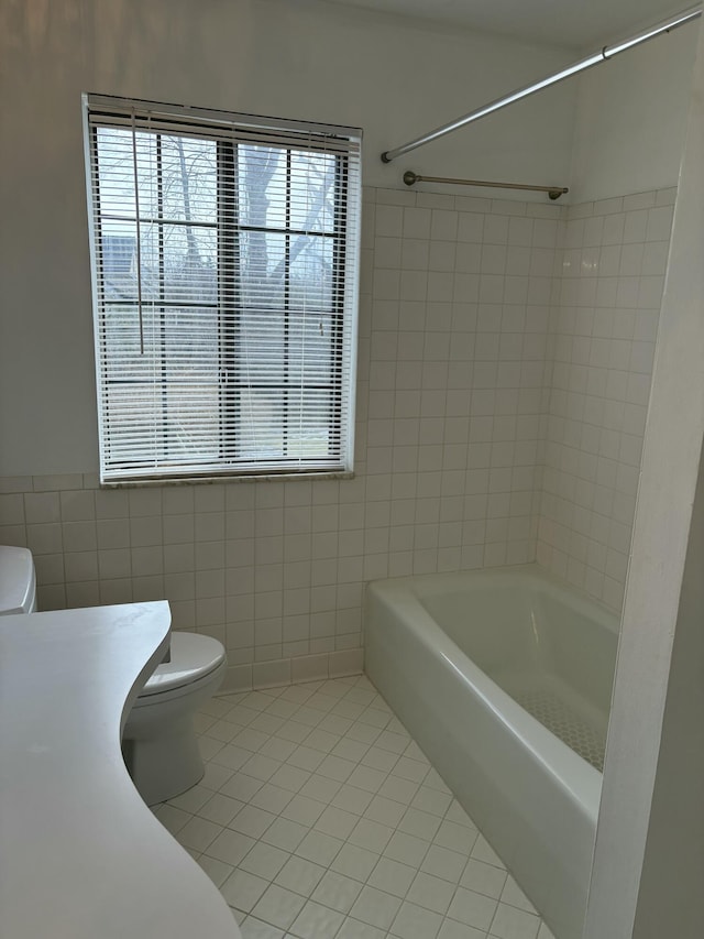 full bathroom featuring toilet, a wealth of natural light, and tile patterned floors