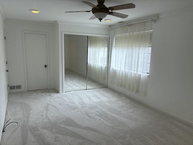 unfurnished bedroom with carpet flooring, visible vents, a ceiling fan, ornamental molding, and a closet