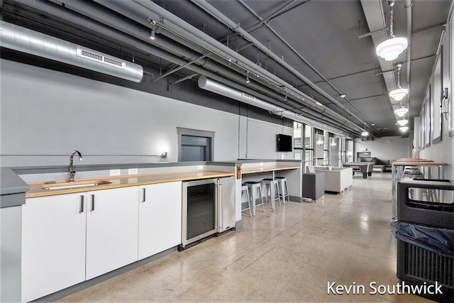 kitchen with white cabinetry, beverage cooler, and sink