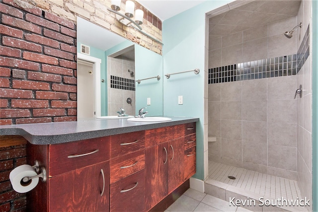 bathroom with tile patterned flooring, vanity, tiled shower, and brick wall