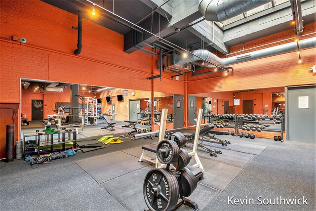 workout area with a towering ceiling and brick wall