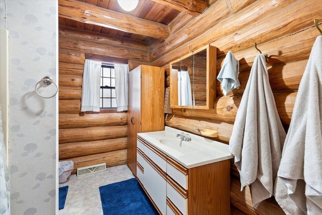 bathroom with beam ceiling, rustic walls, vanity, and wooden ceiling