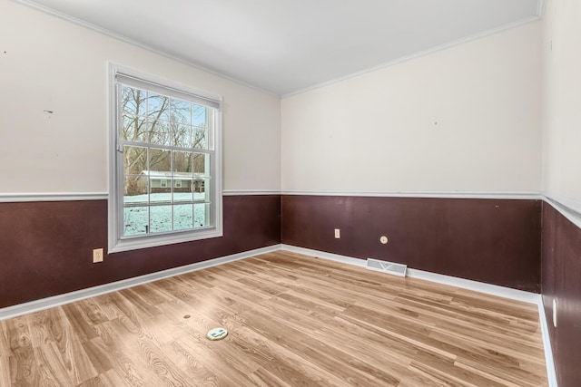 spare room with light hardwood / wood-style floors, ornamental molding, and wooden walls