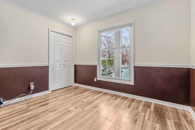 spare room with light wood-type flooring and crown molding