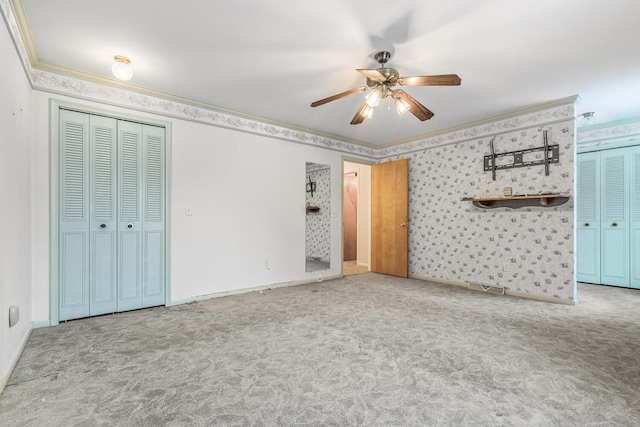 unfurnished bedroom featuring multiple closets, light colored carpet, ceiling fan, and ornamental molding