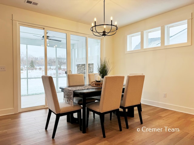 dining space with plenty of natural light, ceiling fan with notable chandelier, and hardwood / wood-style floors