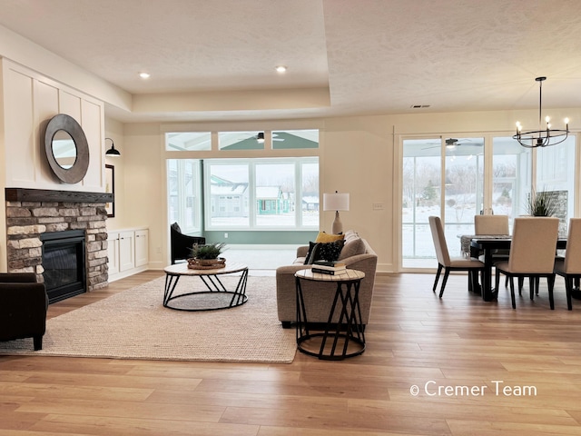 living room featuring a fireplace, an inviting chandelier, and light hardwood / wood-style floors