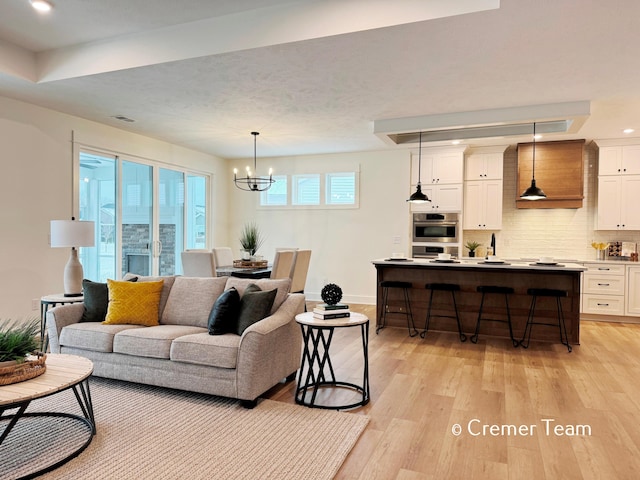 living room with an inviting chandelier and light hardwood / wood-style floors