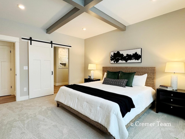 bedroom with carpet, beam ceiling, and a barn door