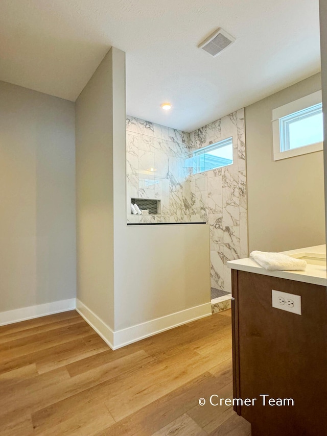 bathroom featuring a tile shower and wood-type flooring