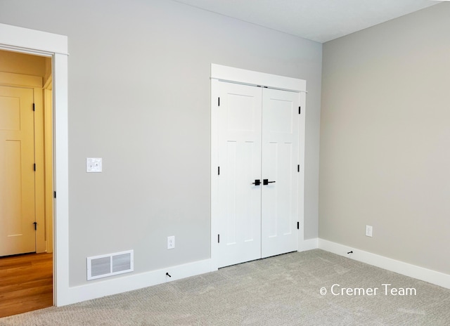 unfurnished bedroom with light carpet and a closet