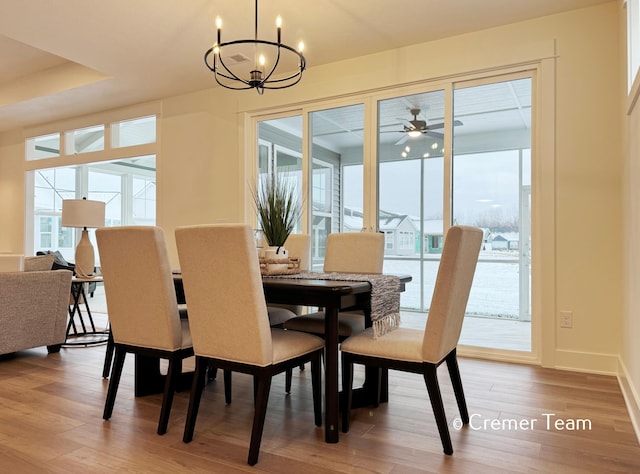 dining room featuring a healthy amount of sunlight, ceiling fan with notable chandelier, and hardwood / wood-style floors