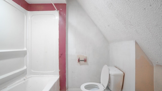 bathroom with a textured ceiling, toilet, and a bath