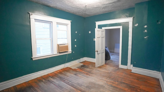 unfurnished room with hardwood / wood-style floors, a textured ceiling, and cooling unit