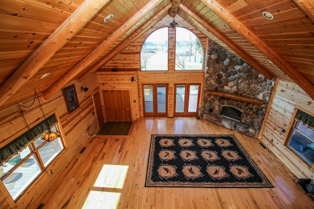 unfurnished living room featuring beam ceiling, wooden ceiling, a stone fireplace, high vaulted ceiling, and light wood-type flooring