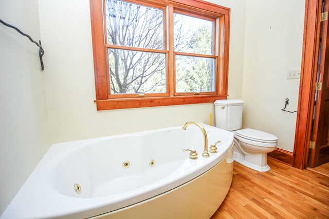 bathroom featuring a washtub, hardwood / wood-style floors, and toilet