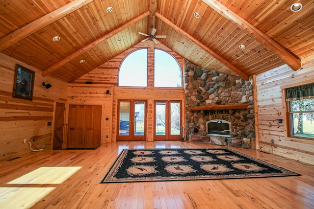 unfurnished living room with a stone fireplace, beamed ceiling, high vaulted ceiling, and wooden ceiling