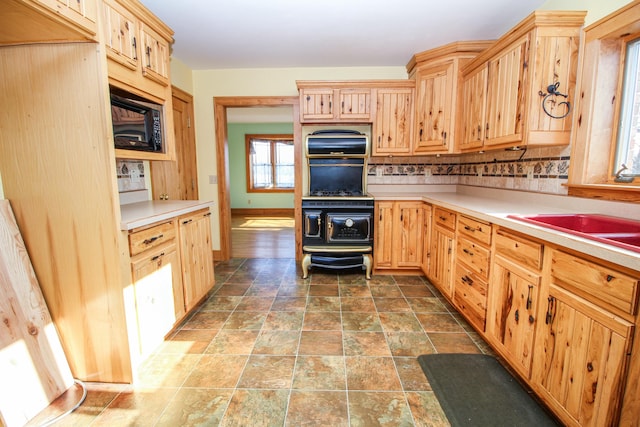 kitchen featuring black appliances, light brown cabinets, and tasteful backsplash