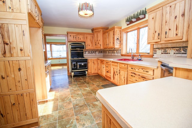 kitchen featuring dishwasher, sink, light brown cabinetry, tasteful backsplash, and decorative light fixtures