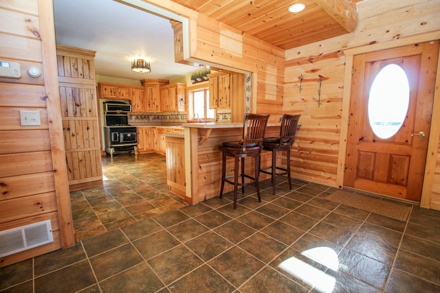 kitchen featuring kitchen peninsula, a kitchen breakfast bar, wooden walls, and wood ceiling