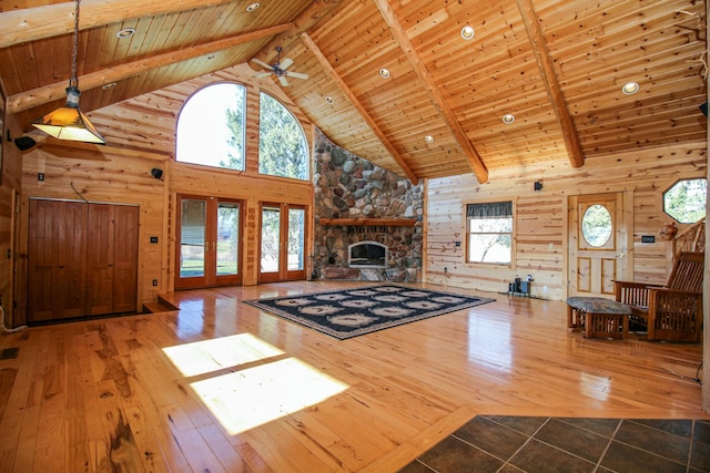 unfurnished living room featuring beam ceiling, a stone fireplace, wooden ceiling, and high vaulted ceiling