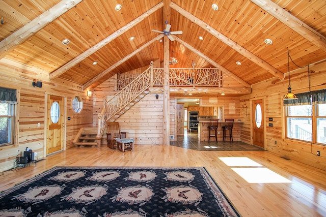 unfurnished living room with beam ceiling, high vaulted ceiling, wood walls, hardwood / wood-style floors, and wood ceiling