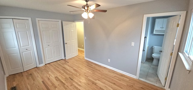 unfurnished bedroom with multiple closets, ensuite bathroom, ceiling fan, and light hardwood / wood-style floors