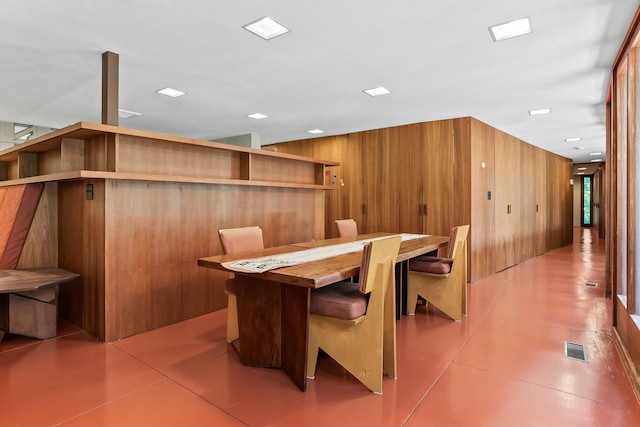 dining area with tile patterned flooring and wood walls