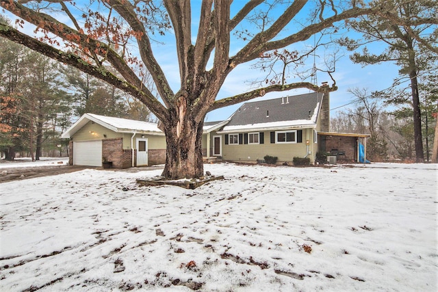 snow covered rear of property featuring a garage