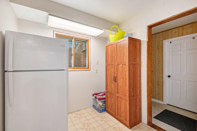 kitchen featuring white fridge and wooden walls