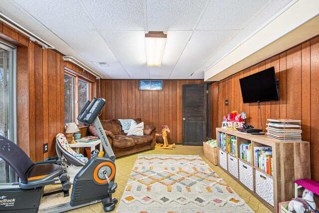 interior space featuring a paneled ceiling and wood walls