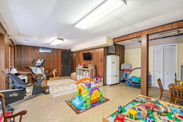 game room with a paneled ceiling and wooden walls