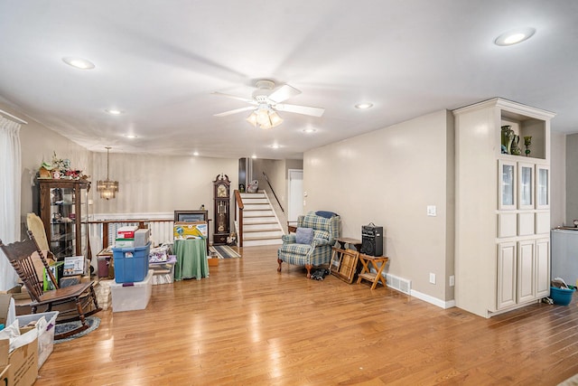 interior space with ceiling fan with notable chandelier and light wood-type flooring