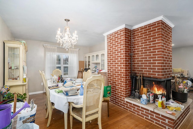 dining room with hardwood / wood-style floors, a notable chandelier, and a brick fireplace