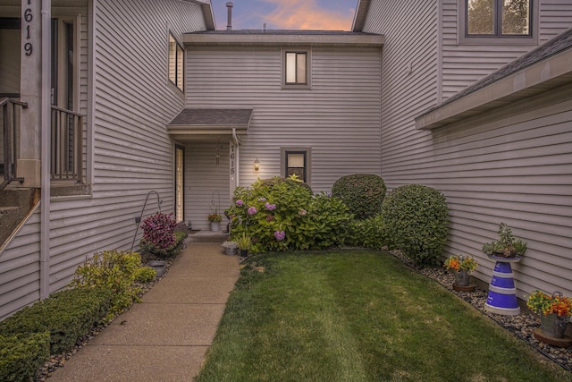 exterior entry at dusk featuring a yard