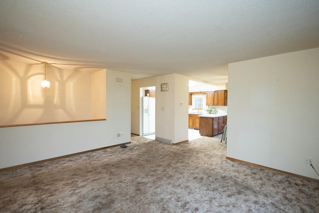 unfurnished living room with light carpet and sink