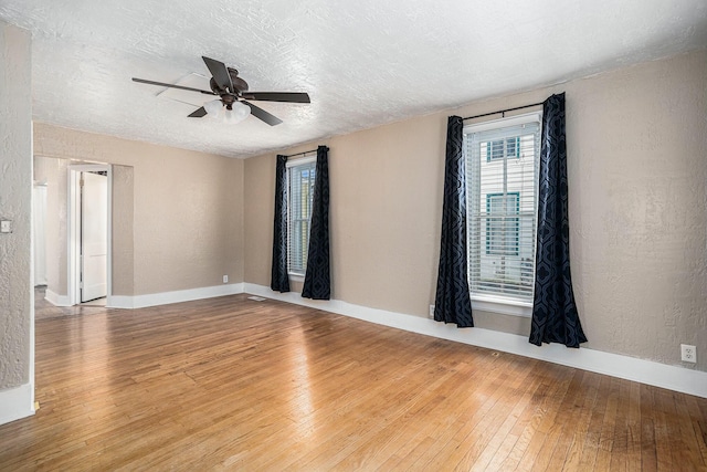 empty room featuring ceiling fan, light wood-type flooring, and a textured ceiling