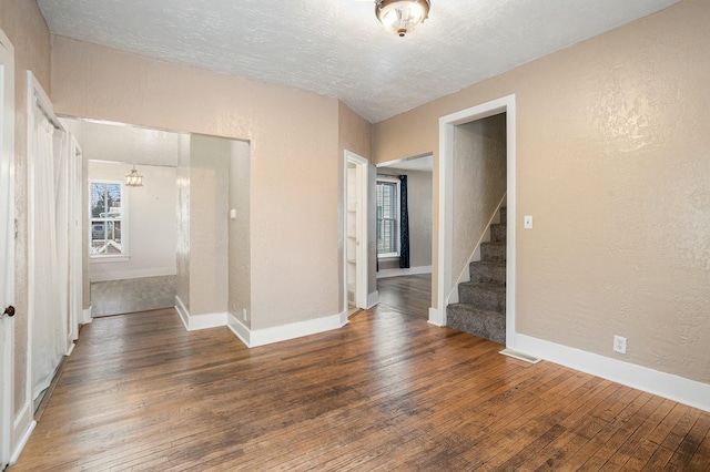 empty room featuring a textured ceiling and dark hardwood / wood-style flooring