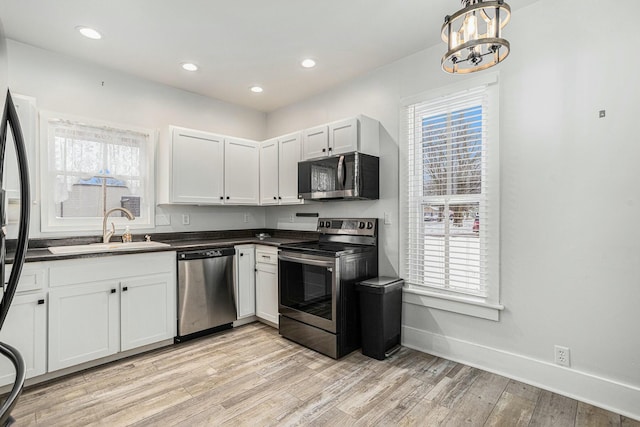 kitchen featuring white cabinetry, sink, stainless steel appliances, a chandelier, and light hardwood / wood-style floors