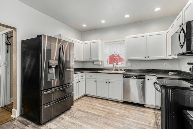 kitchen with white cabinetry, stainless steel appliances, and light wood-type flooring